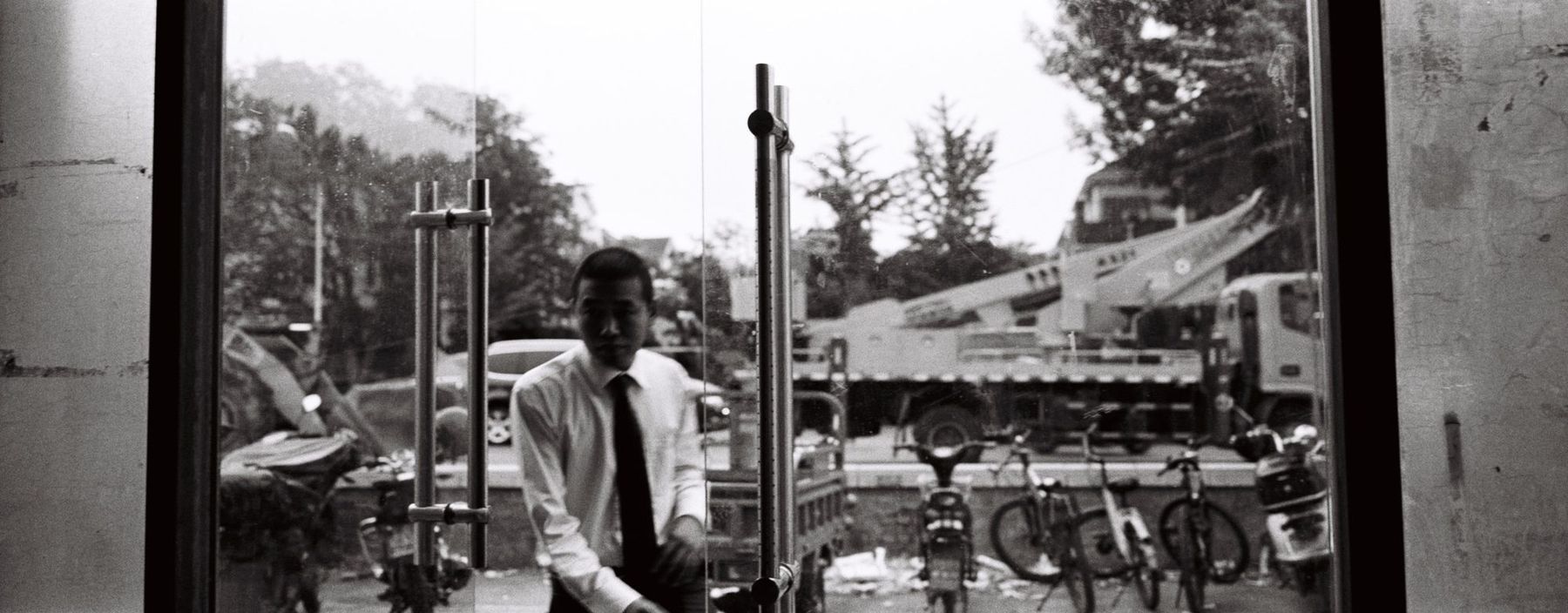 A man in a shirt and tie seen through a shop window