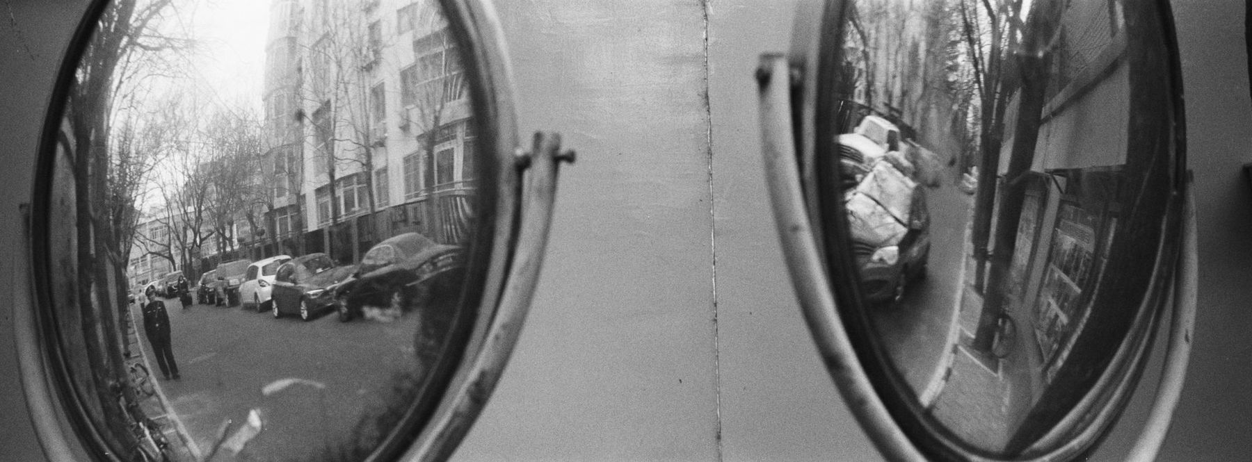 Two round street mirrors reflecting a tree-lined road
