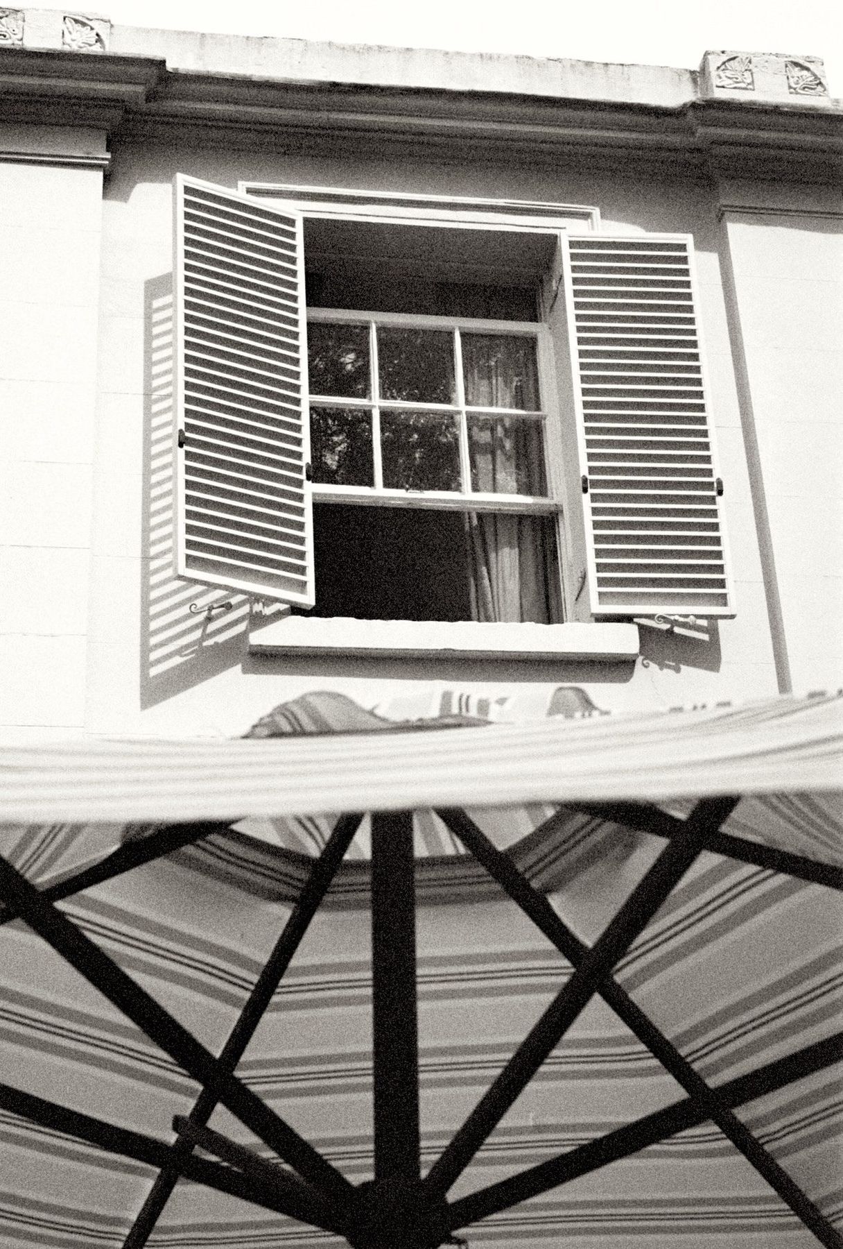 A shuttered window above a striped parasol